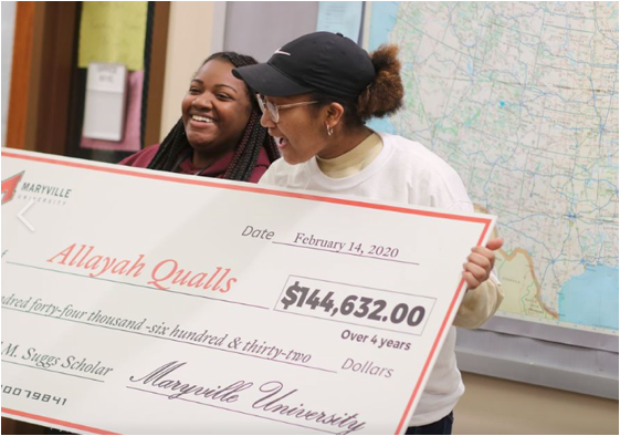 Two students stand holding a large check