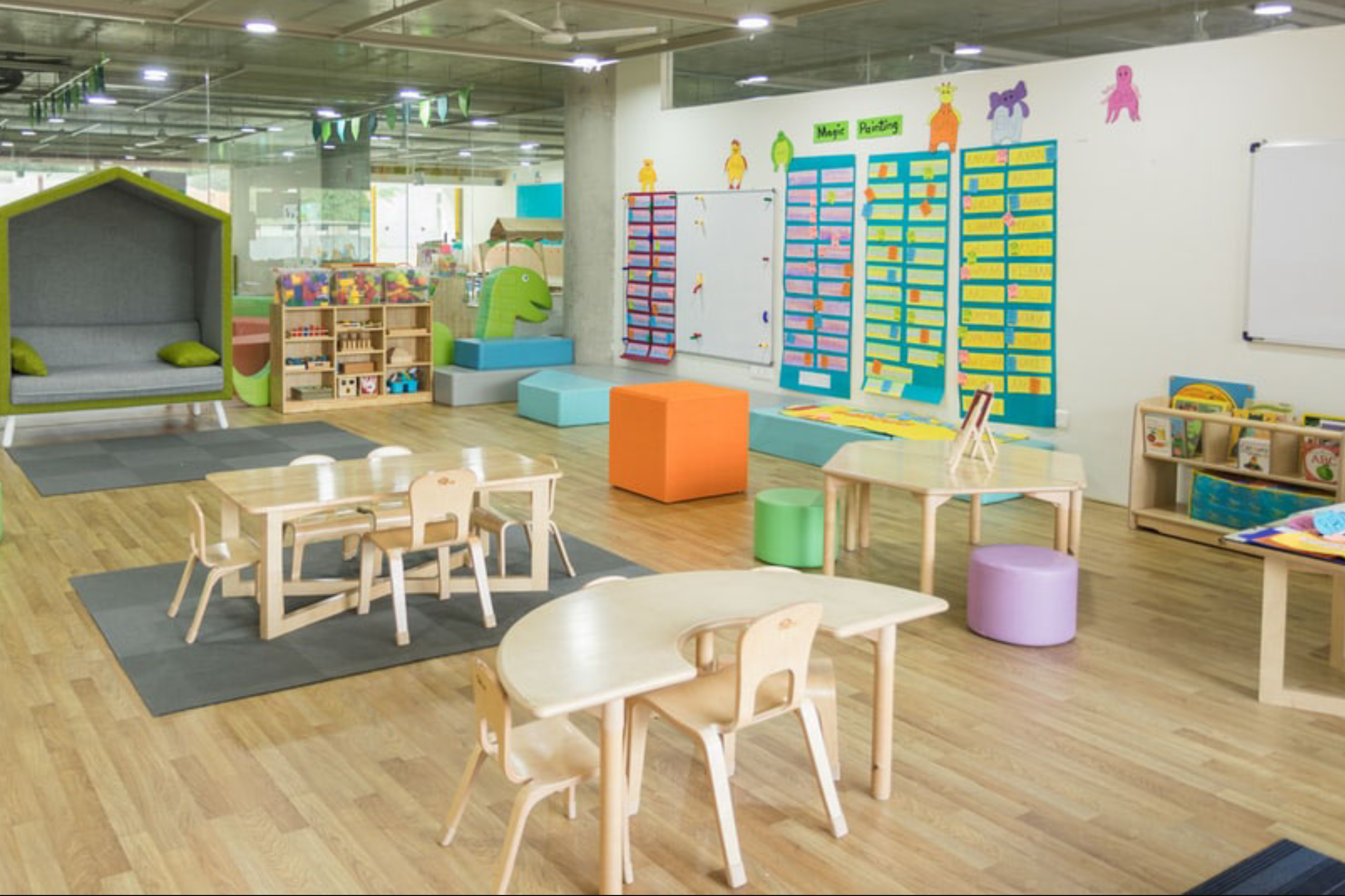Pre-K classroom with tables, chairs, and learning materials on the wall