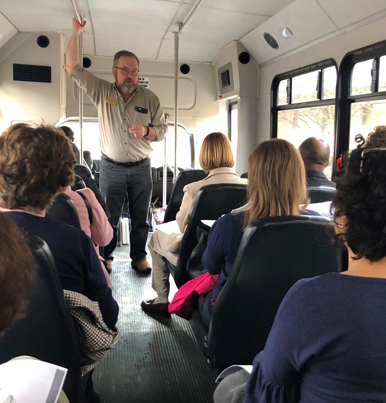 Andy Theising standing on bus talking to seated funders